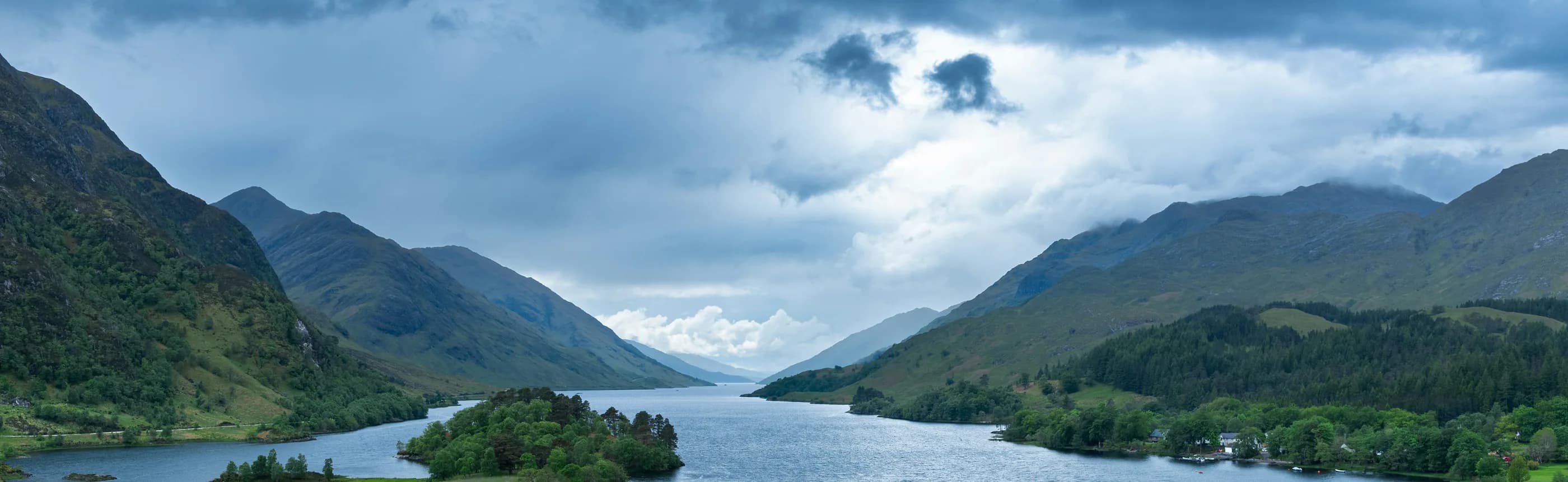 Mountain valley and loch beneath a cloudy sky